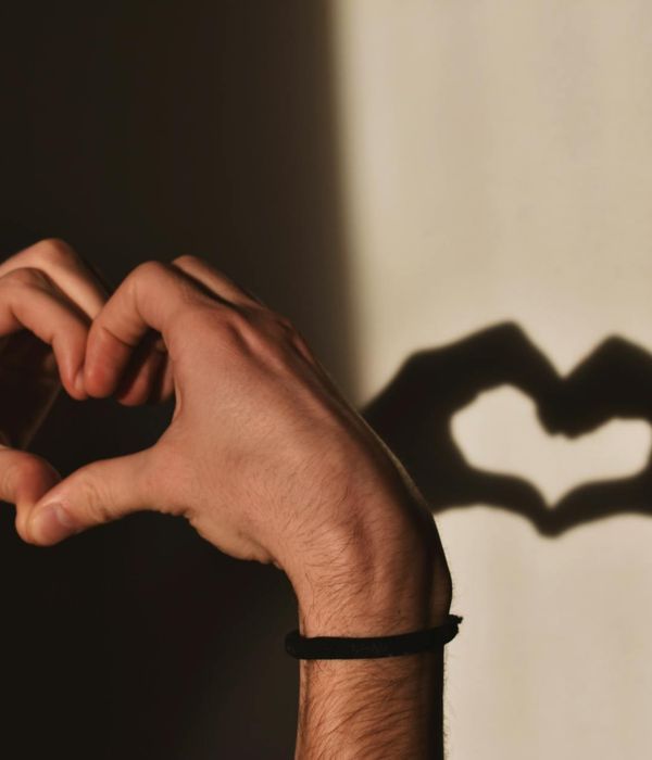 Silhouette of a person in a gentle stretching pose against a dark background.